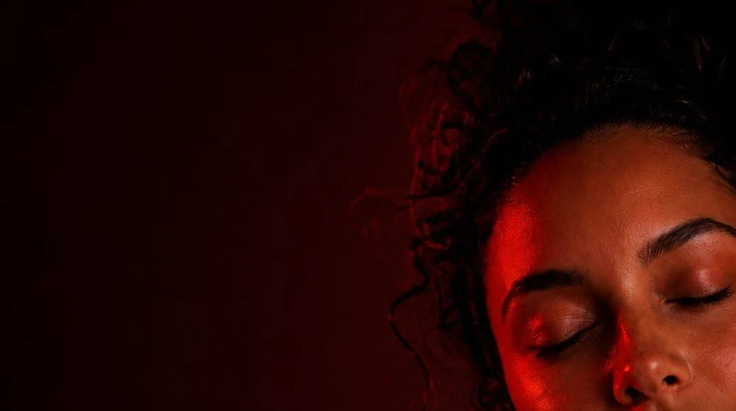 A woman resting with her eyes closed under red light